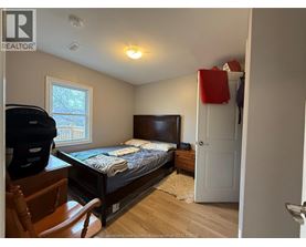 A bedroom with a bed, dresser, and chair.