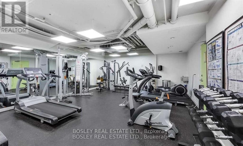 A spacious gym with various exercise equipment and a wall of windows.