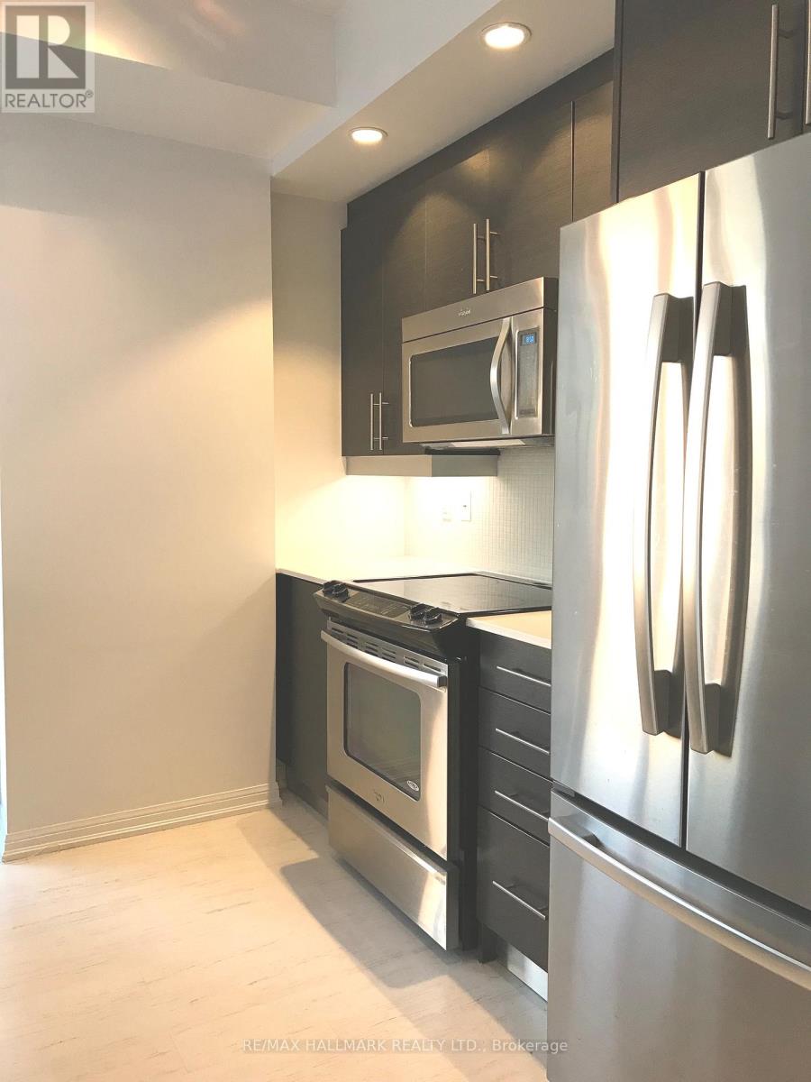 A modern kitchen with a stainless steel refrigerator and microwave above the oven.