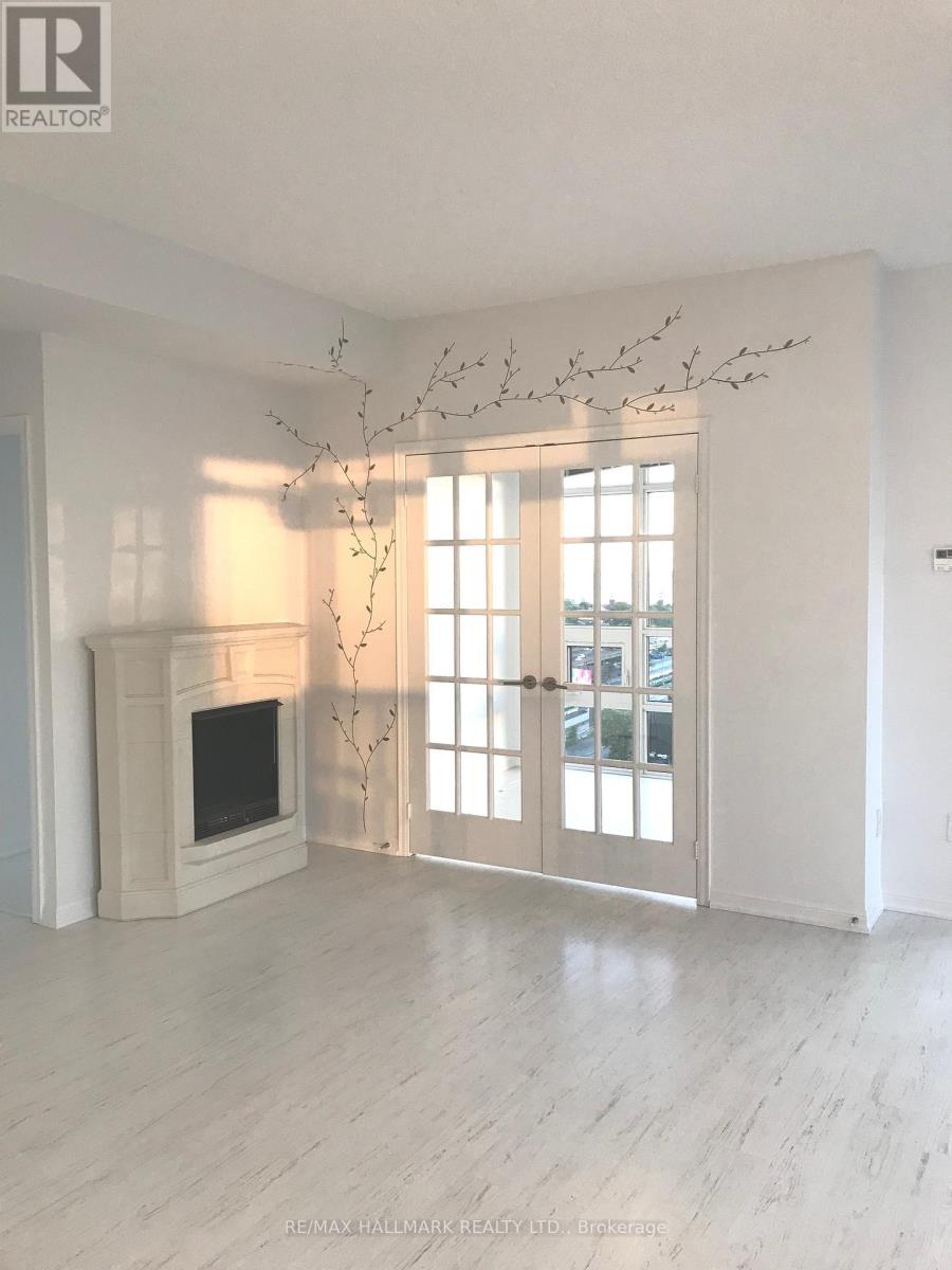 A sparsely furnished living room with a fireplace and a tree branch decoration.