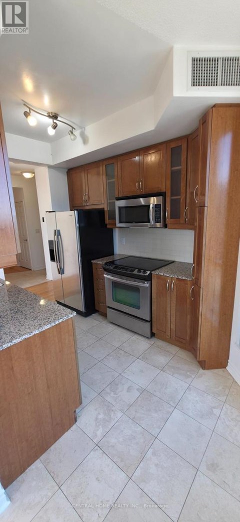 A kitchen with wooden cabinets and a black refrigerator.