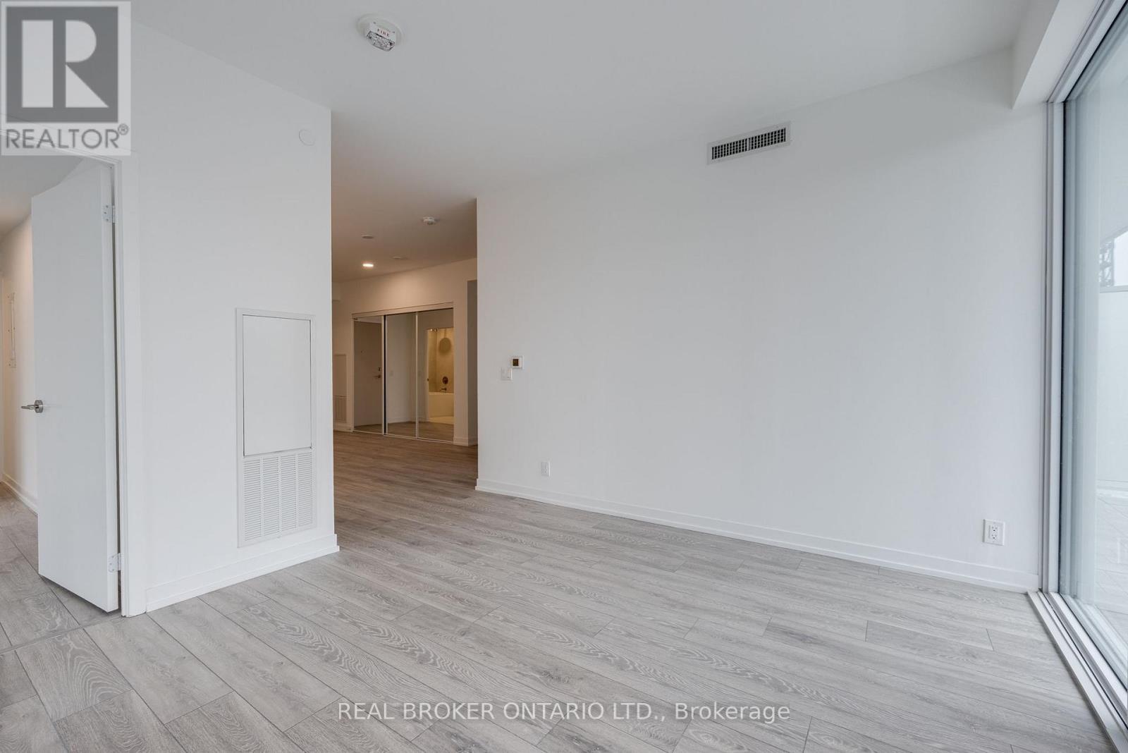 A spacious room with wood flooring and white walls.