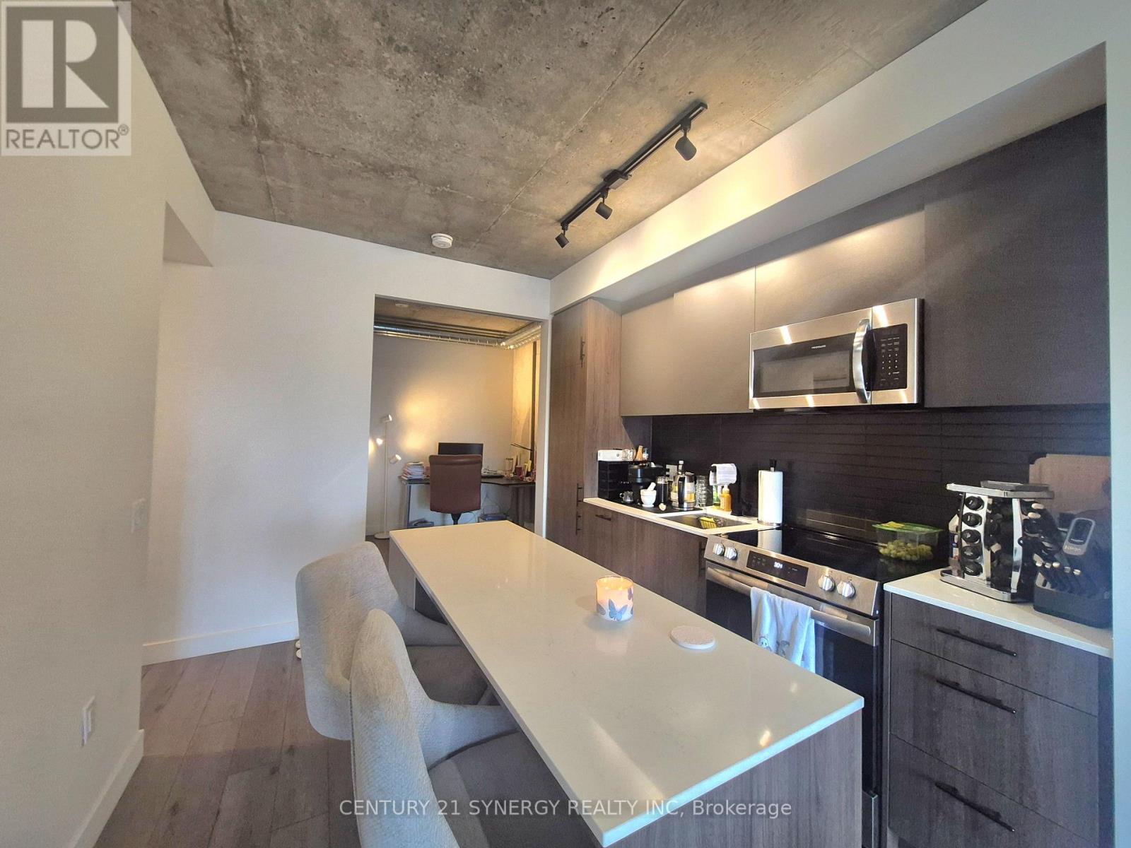 A modern kitchen with a long white island and a microwave above it.