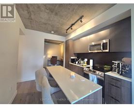 A modern kitchen with a long white island and a microwave above it.
