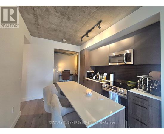 A modern kitchen with a long white island and a microwave above it.