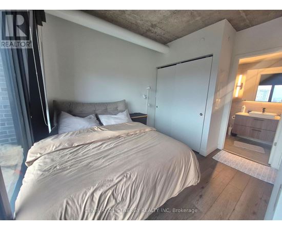 A bedroom with a bed, a nightstand, and a mirror.