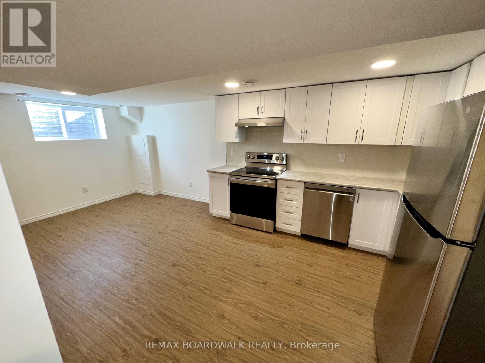 A kitchen with white cabinets and a wooden floor.