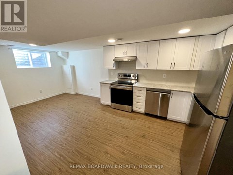A kitchen with white cabinets and a wooden floor.