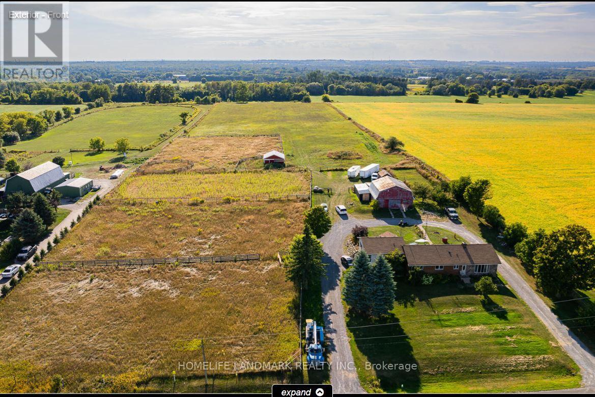 An aerial view of a rural property with a large field, a few buildings, and a road.