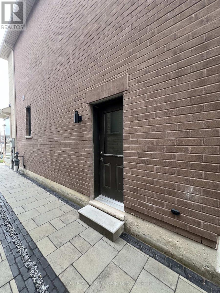 A brown brick building with a black door and a small window.