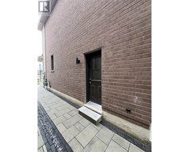 A brown brick building with a black door and a small window.