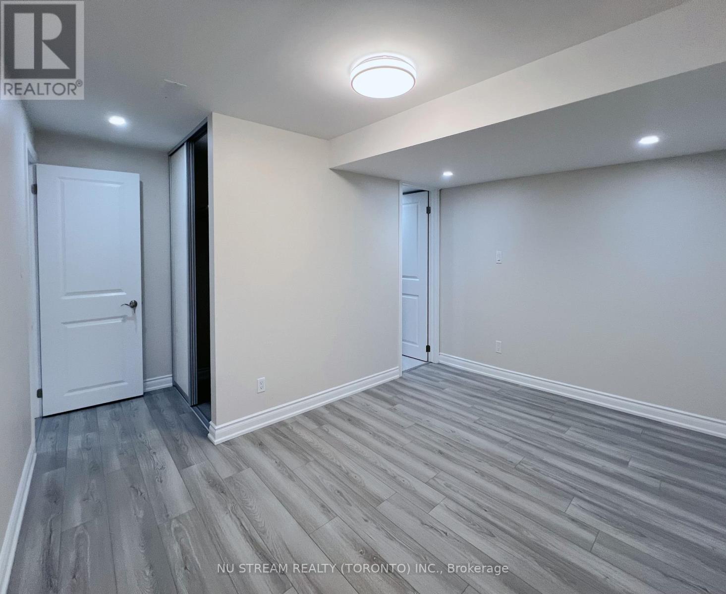 A room with a white door and a grey floor.