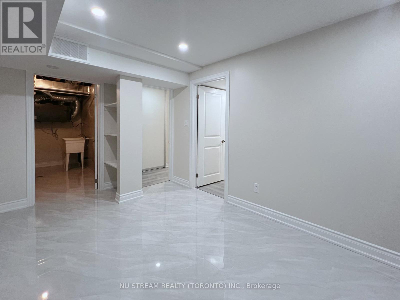 A spacious room with marble flooring and white walls, with a doorway leading to another room.