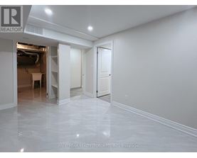 A spacious room with marble flooring and white walls, with a doorway leading to another room.