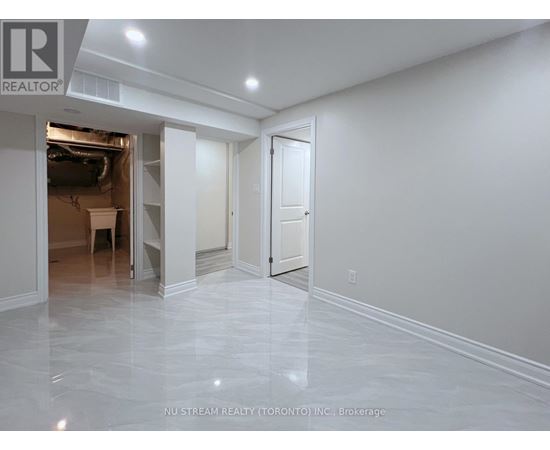 A spacious room with marble flooring and white walls, with a doorway leading to another room.