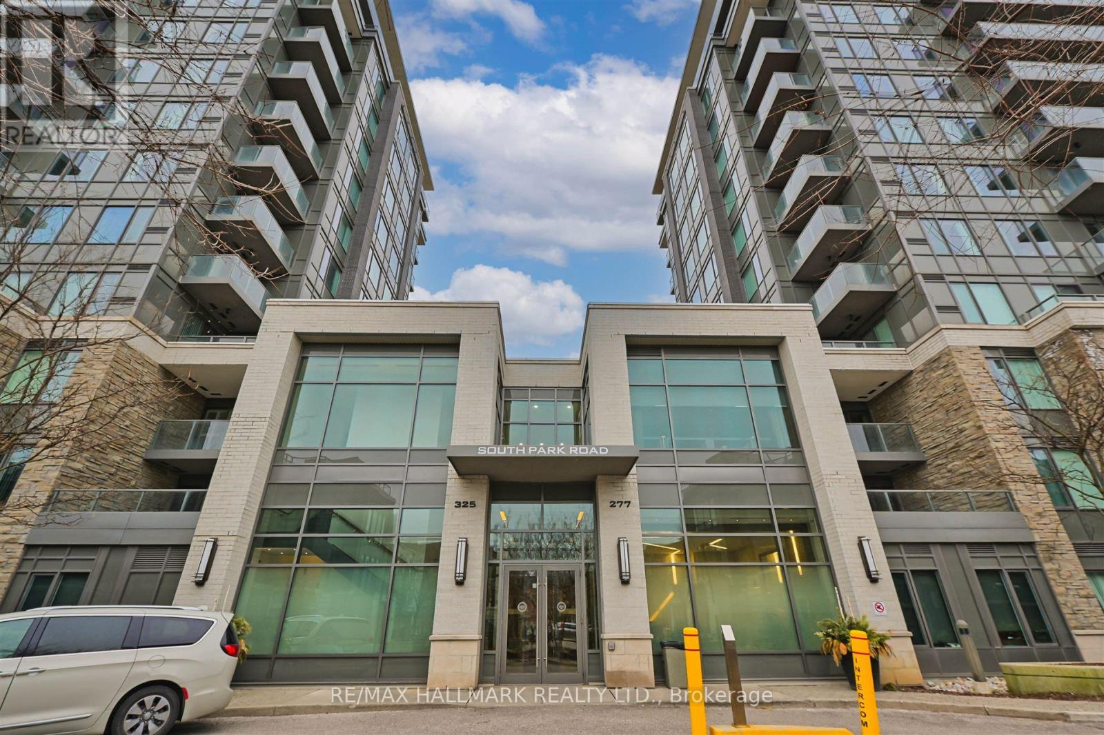 The image shows a modern building with a glass facade and a stone entrance.