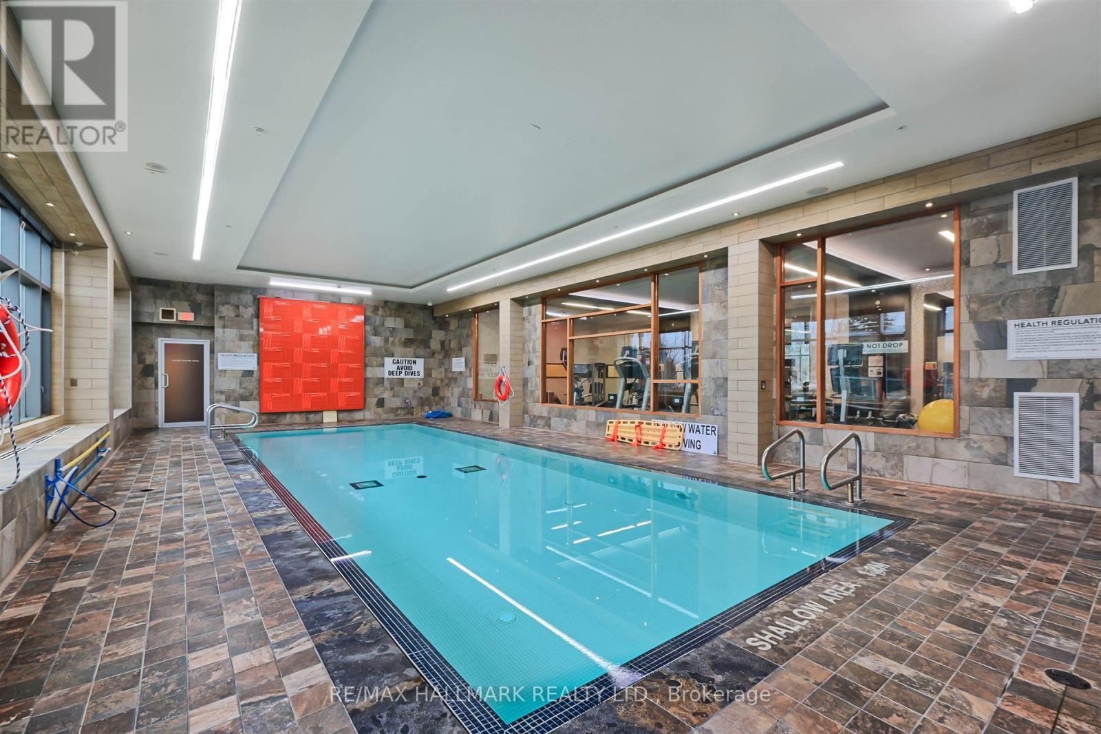 A large indoor swimming pool with a tiled floor and a stone wall.