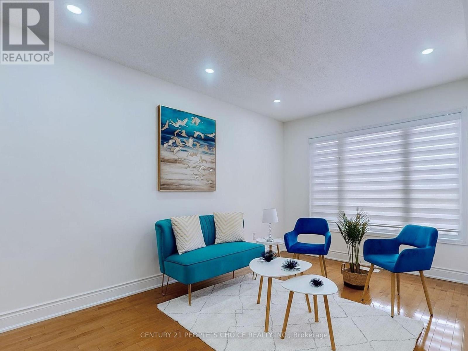 A living room with a blue sofa and a painting on the wall.