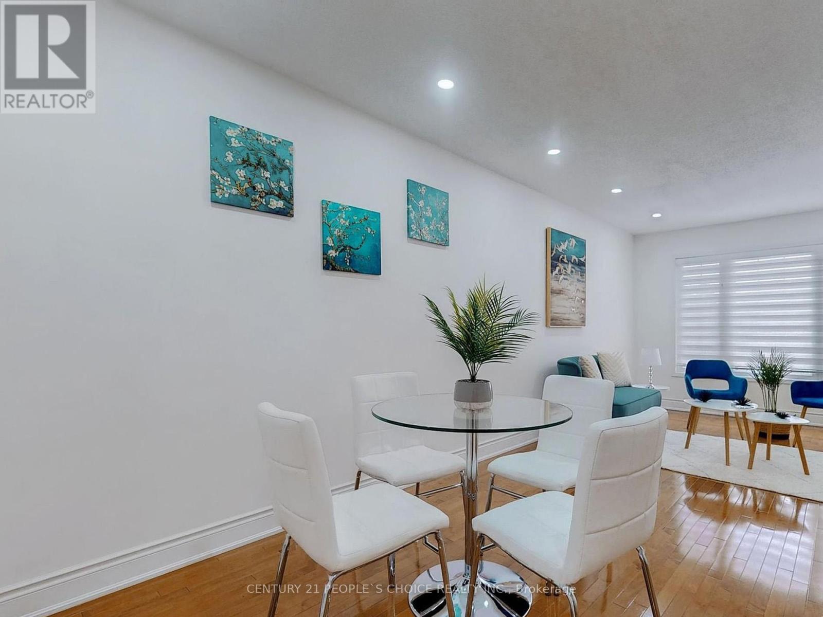 A dining room with a glass table and white chairs.