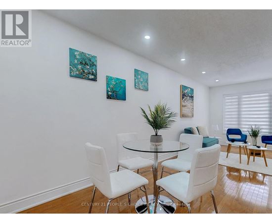 A dining room with a glass table and white chairs.
