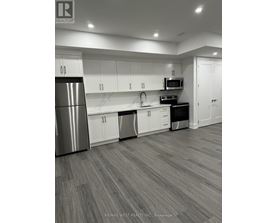 A modern kitchen with white cabinets and a stainless steel refrigerator.