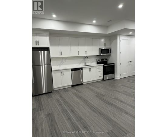 A modern kitchen with white cabinets and a stainless steel refrigerator.