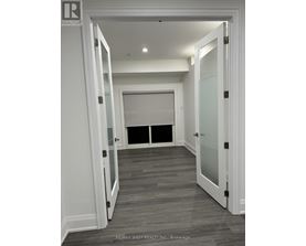 A hallway with white walls and a wooden floor.