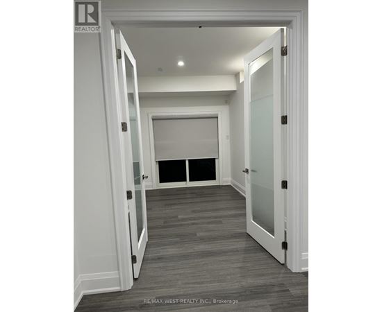 A hallway with white walls and a wooden floor.