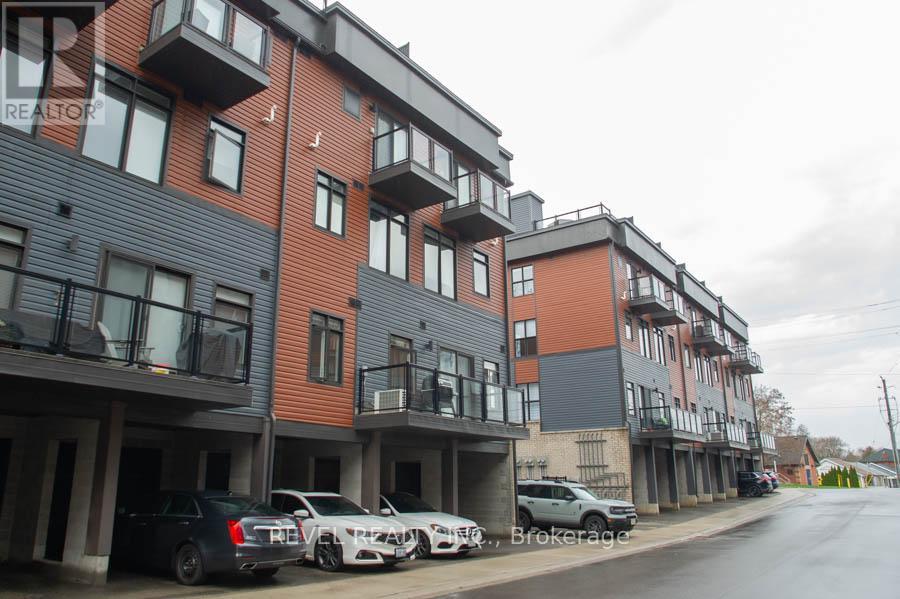 A row of modern apartment buildings with cars parked in front.