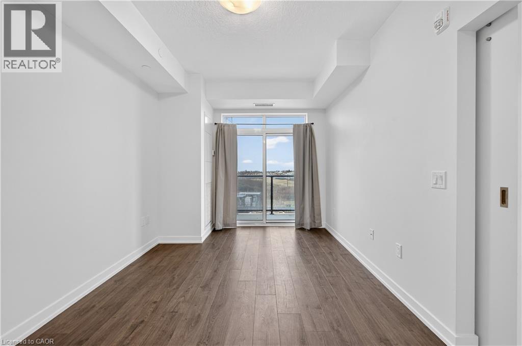 A spacious room with wooden flooring and a sliding glass door leading to a balcony.