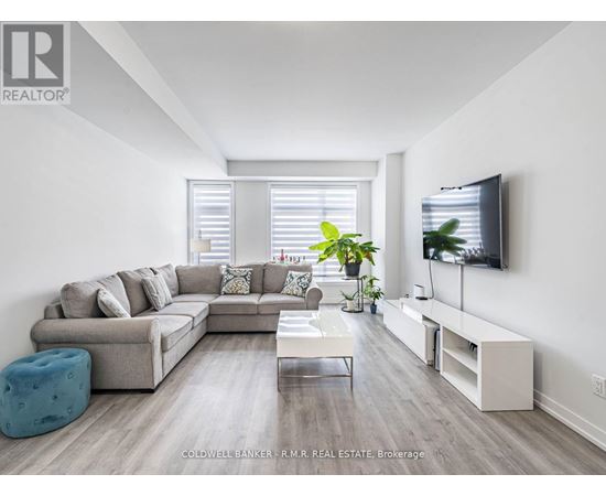 A modern living room with a grey sofa, a white coffee table, and a television on the wall.