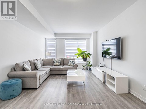 A modern living room with a grey sofa, a white coffee table, and a television on the wall.