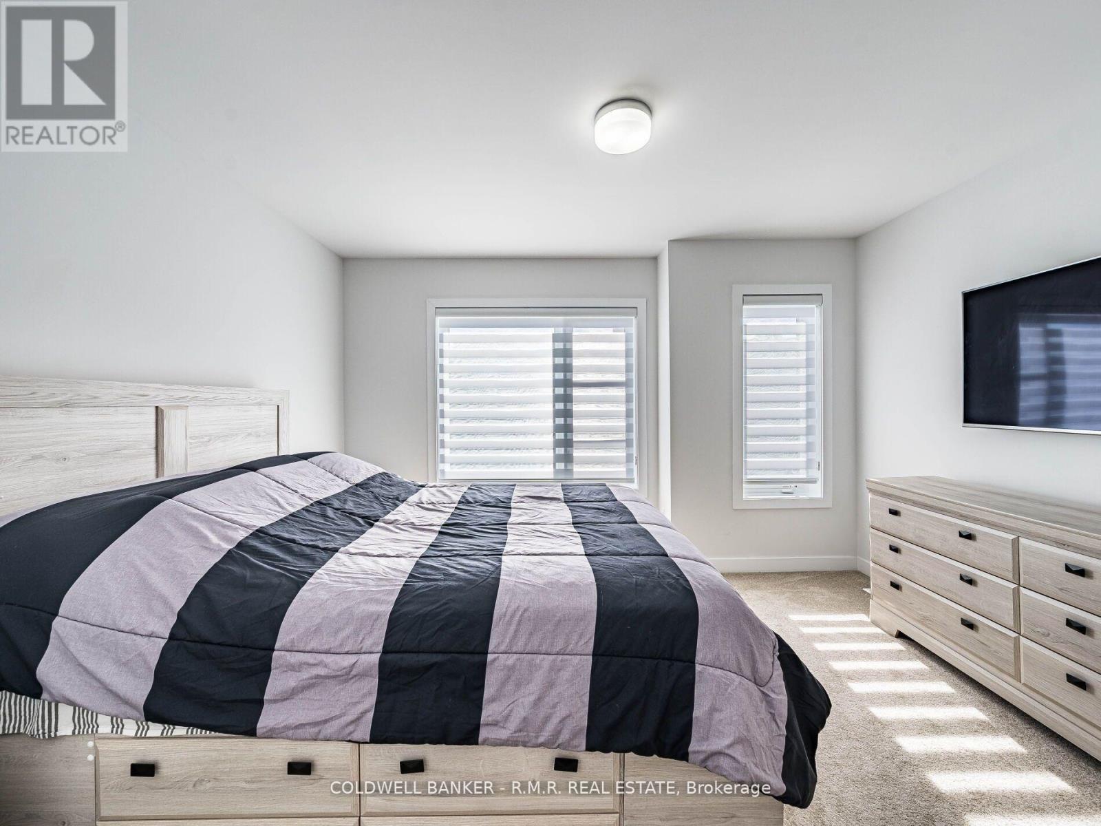 A bedroom with a bed, dresser, and window with blinds.