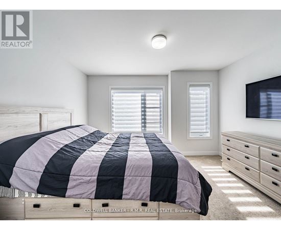 A bedroom with a bed, dresser, and window with blinds.