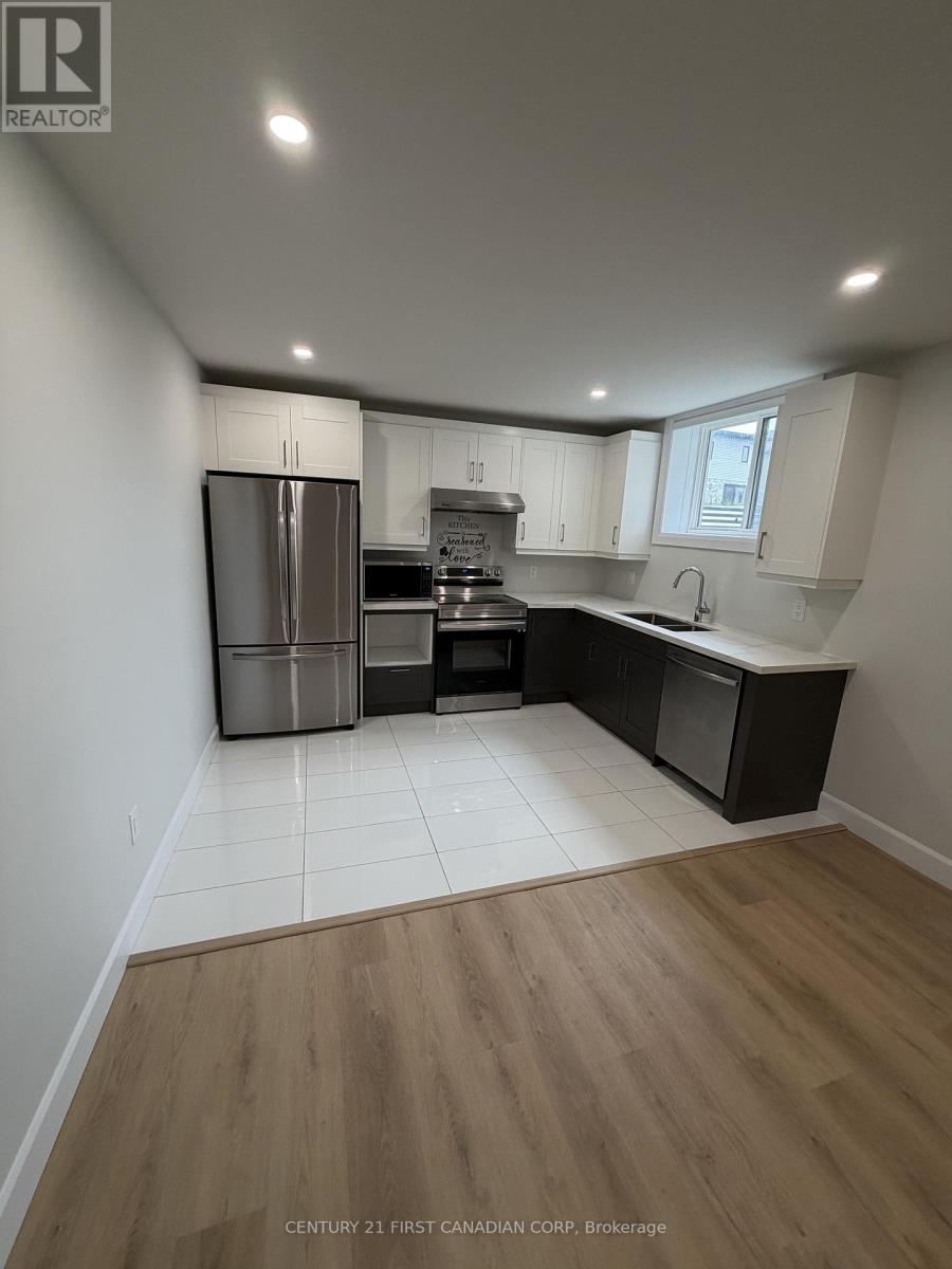A kitchen with a refrigerator, oven, and sink.