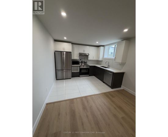 A kitchen with a refrigerator, oven, and sink.
