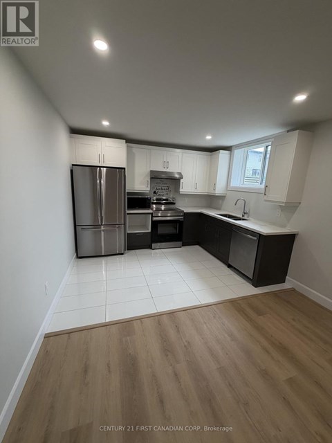 A kitchen with a refrigerator, oven, and sink.