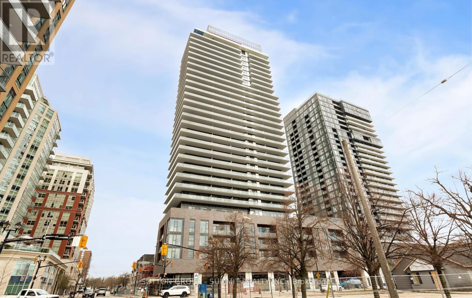 A tall building with a curved facade stands in front of two other buildings.
