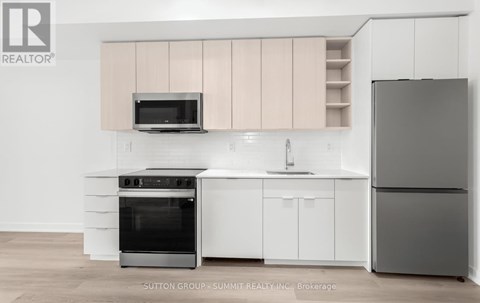 A modern kitchen with white cabinets and a black refrigerator.