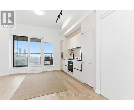 A kitchen with white cabinets and a beige rug on the floor.