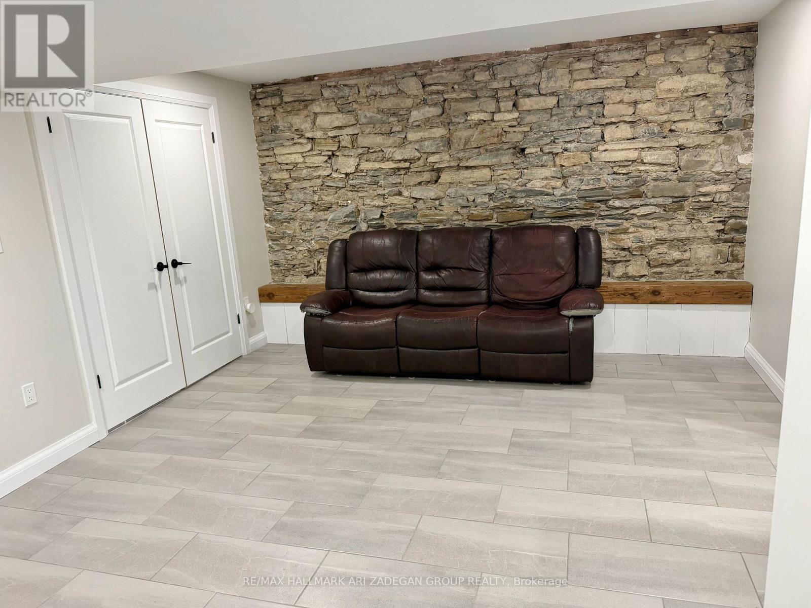 A living room with a brown couch and a stone wall.