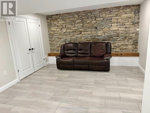 A living room with a brown couch and a stone wall.