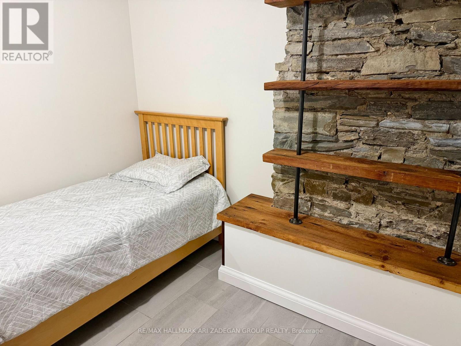 A bedroom with a bed and a stone wall.