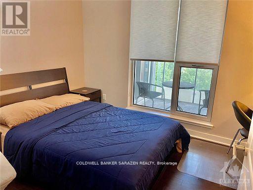 A bedroom with a bed, chair, and window.