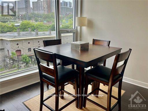 A dining room with a table and chairs in front of a window overlooking a cityscape.