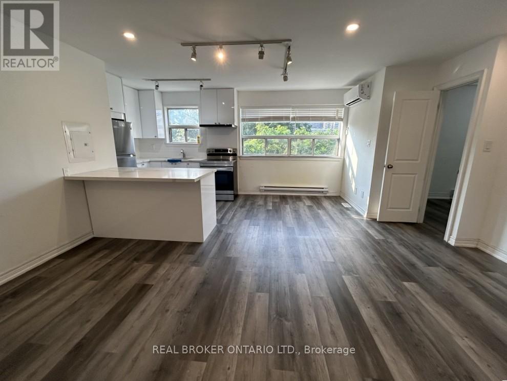 A spacious kitchen and living room with wood flooring and white walls.