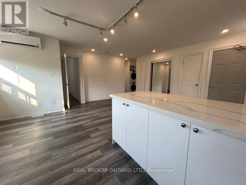 A spacious room with white cabinets and a wooden floor.