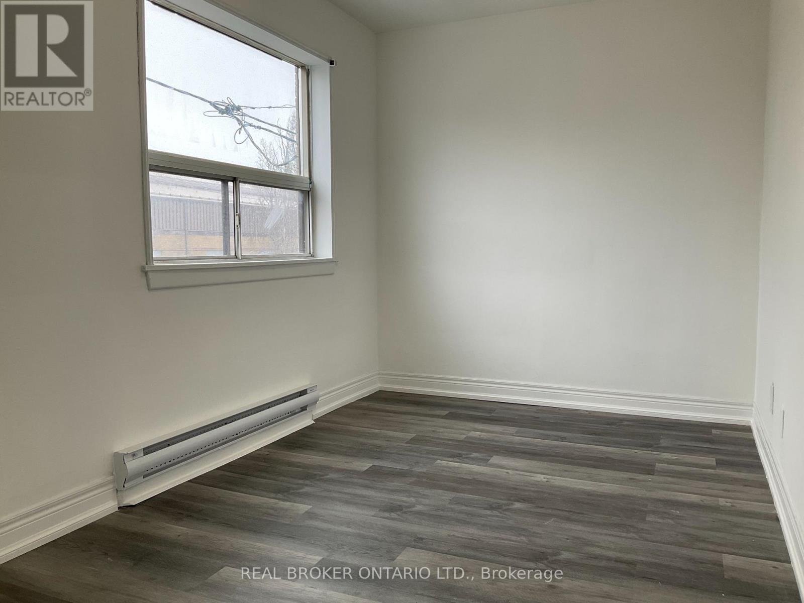 A room with a window and a wooden floor.