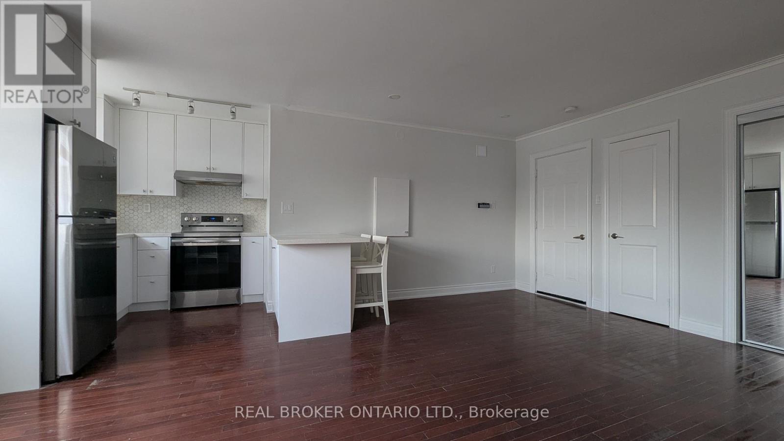 A white kitchen with a refrigerator, sink, and cabinets.