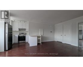 A white kitchen with a refrigerator, sink, and cabinets.